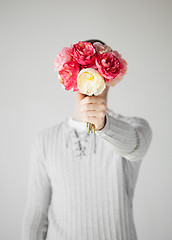 Image showing man covering his face with bouquet of flowers