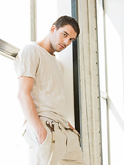 Image showing handsome man standing on the windowsill