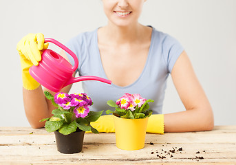 Image showing housewife with flower in pot and watering can