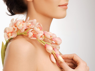 Image showing woman's shoulder and hands holding orchid flower