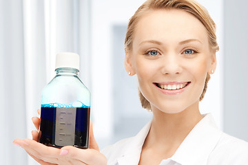 Image showing lab worker holding up bottle with blue liquid