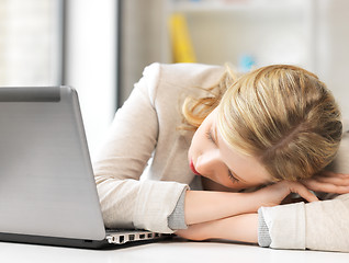 Image showing bored and tired woman sleeping on the table