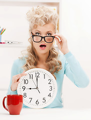 Image showing wondering businesswoman with clock
