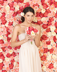 Image showing woman with bouquet and background full of roses