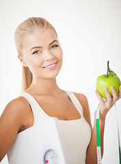 Image showing sporty woman with scale, apple and measuring tape