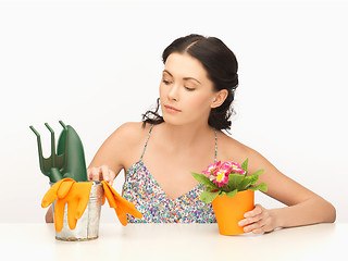 Image showing housewife with flower in pot and gardening set