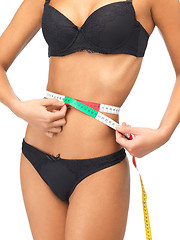 Image showing woman measuring her waist with measuring tape