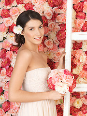 Image showing woman with bouquet and background full of roses