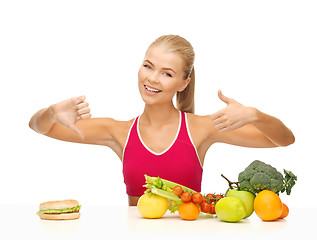 Image showing woman with fruits and hamburger comparing food