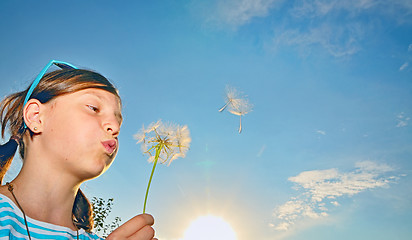 Image showing Young girl blowing dandelion