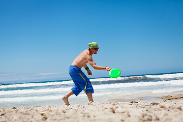 Image showing attractive man playing frisby on beach in summer