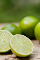 Image showing green fresh lime on wooden table macro closeup outdoor