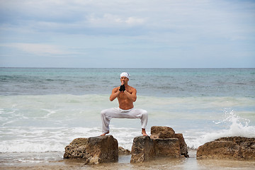 Image showing healthy man doing pilates yoga meditation on beach summer