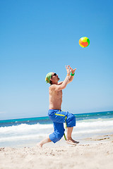 Image showing attractive young man playing volleyball on the beach