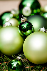 Image showing shiny green christmas baubles closeup macro and tree 