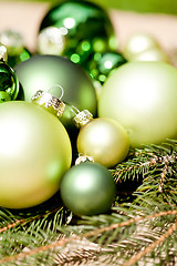 Image showing shiny green christmas baubles closeup macro and tree 