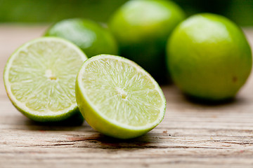 Image showing green fresh lime on wooden table macro closeup outdoor