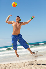 Image showing attractive young man playing volleyball on the beach