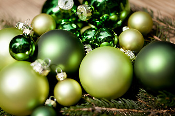 Image showing shiny green christmas baubles closeup macro and tree 