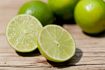 Image showing green fresh lime on wooden table macro closeup outdoor