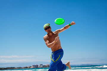 Image showing attractive man playing frisby on beach in summer