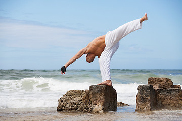 Image showing healthy man doing pilates yoga meditation on beach summer