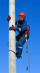 Image showing Electrician climbs the pole transmission line