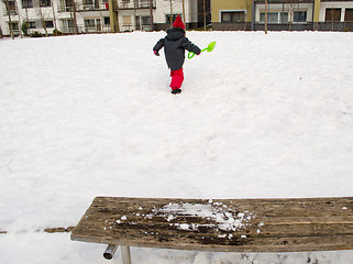 Image showing little girl green shovel snow climbs mountain 
