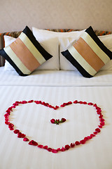 Image showing Heart of rose petals laid out on the bed