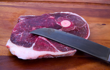 Image showing Raw meat with knife on kitchen board