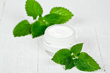 Image showing face cream in glass jar with green leaves of urtica