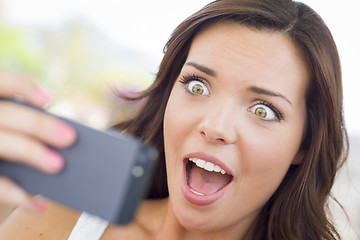 Image showing Shocked Young Adult Female Reading Cell Phone Outdoors