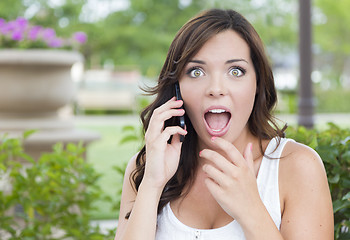 Image showing Shocked Young Adult Female Talking on Cell Phone Outdoors