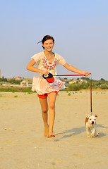 Image showing girl running with her dog on the sand 