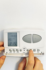 Image showing hand pressing button on digital thermostat