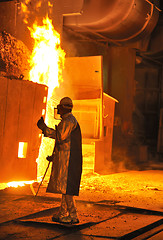 Image showing A steel worker takes a sample from oven