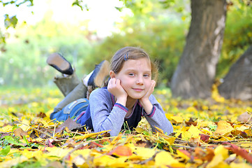 Image showing little girl lays on the leaves