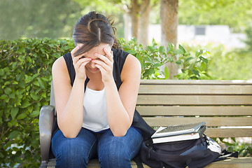 Image showing Upset Young Woman Sitting Alone on Bench Next to Books