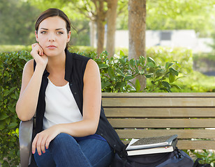 Image showing Melancholy Young Adult Woman Sitting on Bench Next to Books
