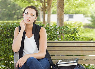 Image showing Melancholy Young Adult Woman Sitting on Bench Next to Books
