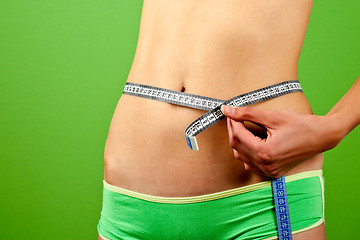 Image showing young woman measuring her slim body 