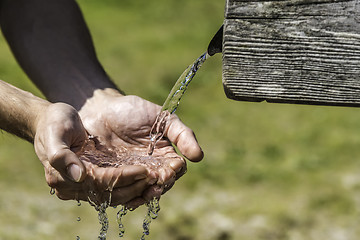 Image showing Thirsty Hands taking water from well