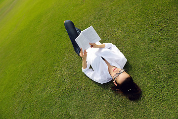 Image showing Young woman reading a book in the park