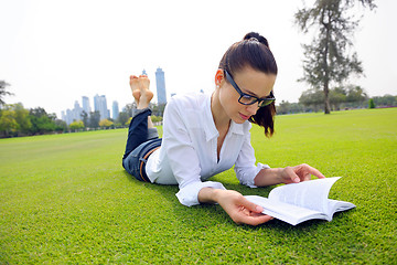 Image showing Young woman reading a book in the park