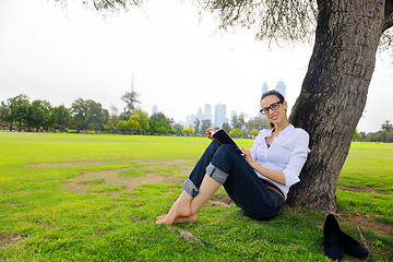 Image showing Young woman reading a book in the park