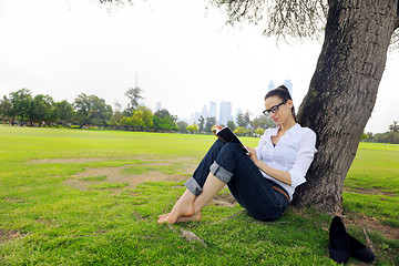 Image showing Young woman reading a book in the park