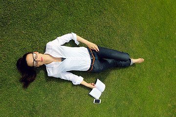 Image showing Young woman reading a book in the park