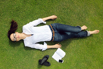 Image showing Young woman reading a book in the park