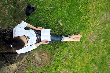 Image showing Young woman reading a book in the park