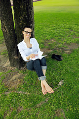 Image showing Young woman reading a book in the park